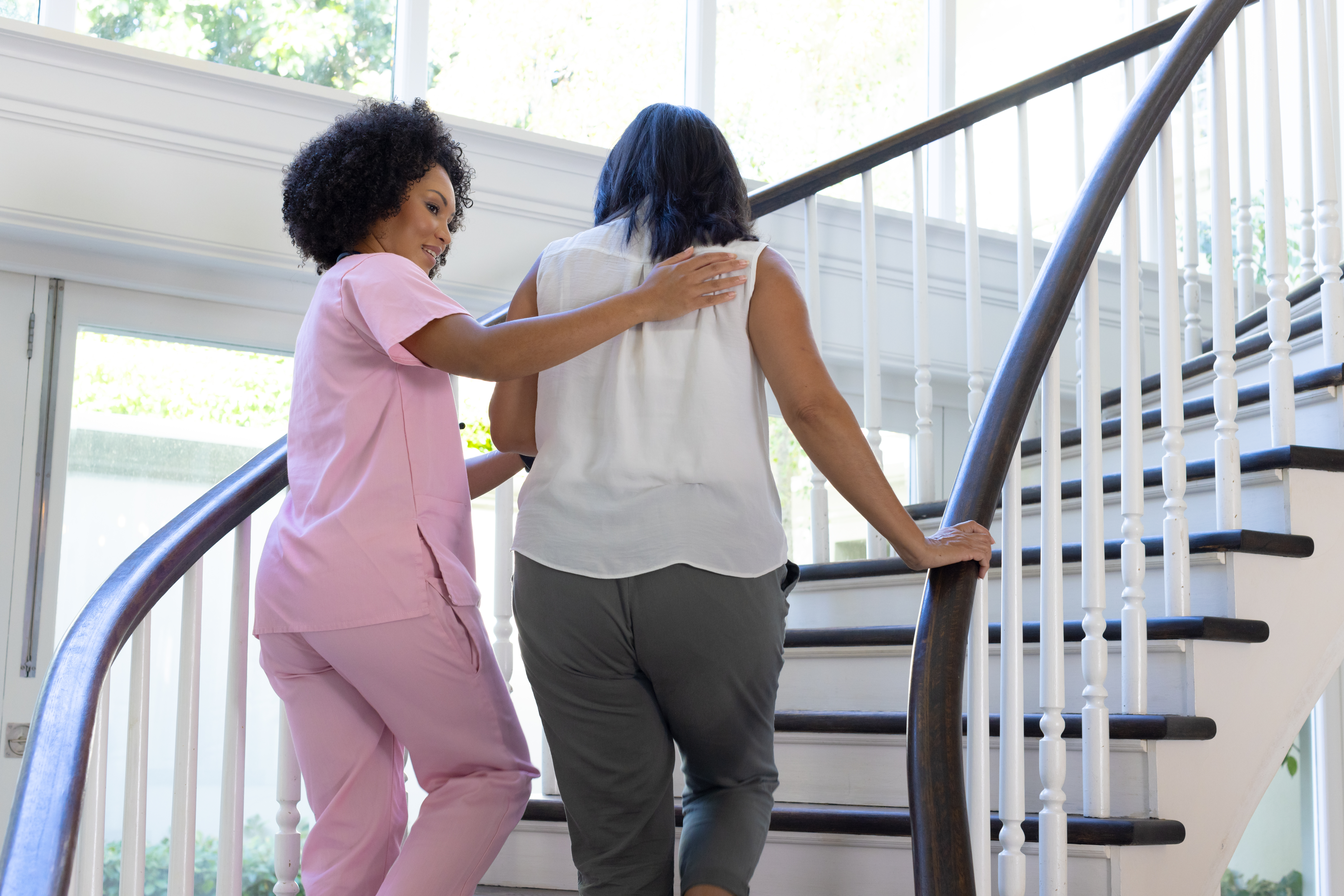 in-home caregiver assiting client up a staircase