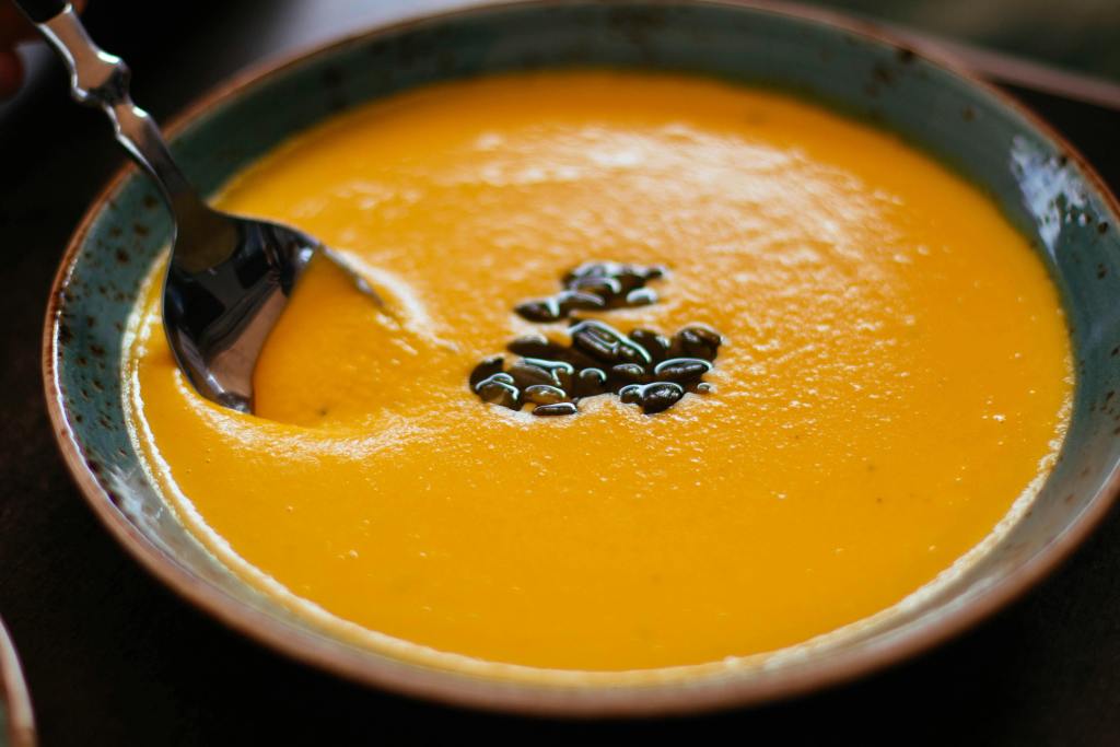 Close-up of creamy pumpkin soup with seeds in a blue ceramic bowl, perfect for a warm fall meal.