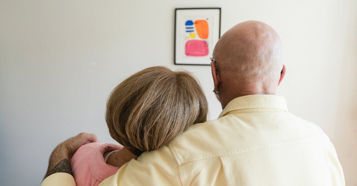 An elderly couple embracing while looking at art on a wall, representing love and companionship.